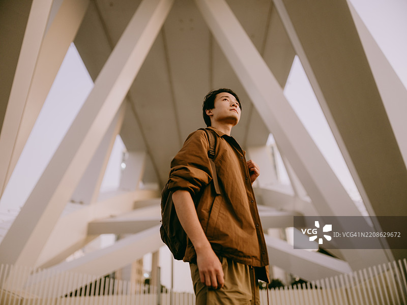 年轻的亚洲男子站在现代桥下图片素材
