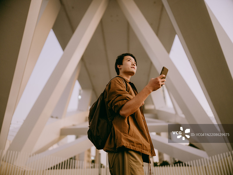 年轻的亚洲男子站在现代桥下图片素材