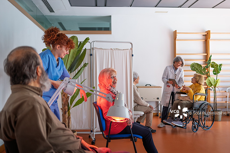 护士在物理治疗诊所使用红外灯为老年患者治疗，促进疼痛缓解和康复。图片素材