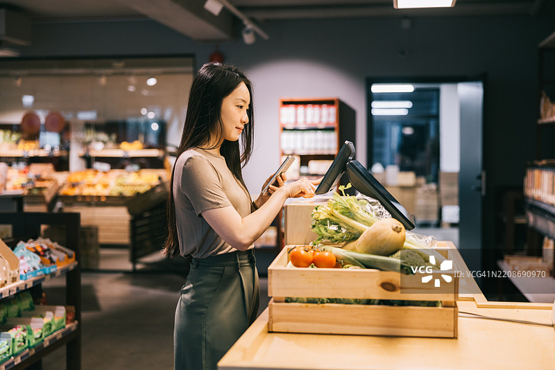 女性顾客在有机商店享受自助终端的便利图片素材
