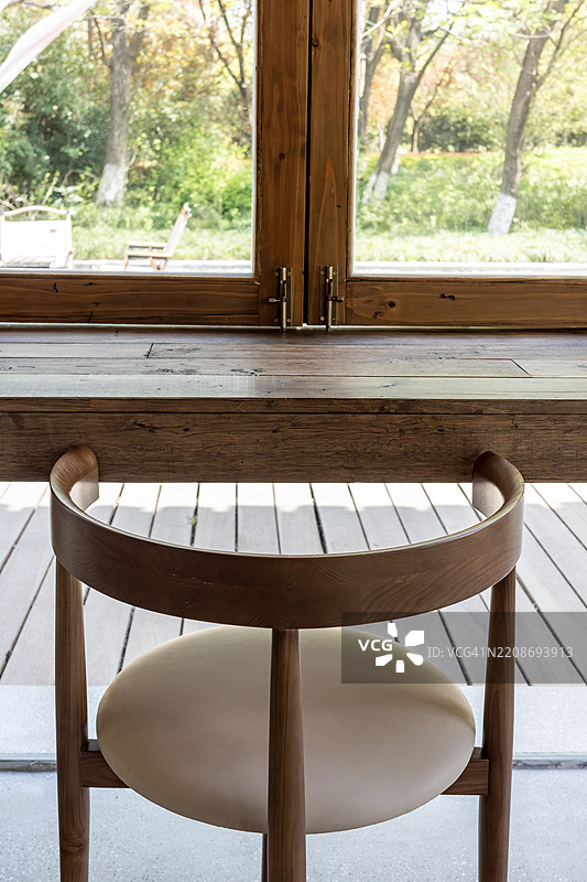 面向大窗户的木质靠背椅，俯瞰花园图片素材