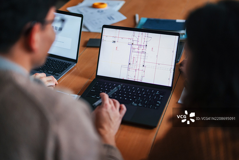 建筑团队在现代工作空间中协作，使用数字蓝图进行项目讨论图片素材
