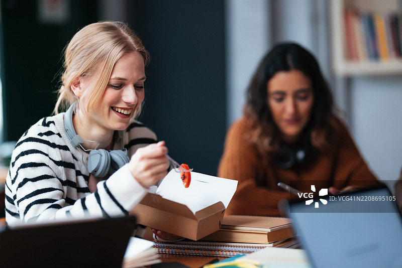 学生们在舒适的咖啡馆环境中边吃午餐边进行学习讨论图片素材