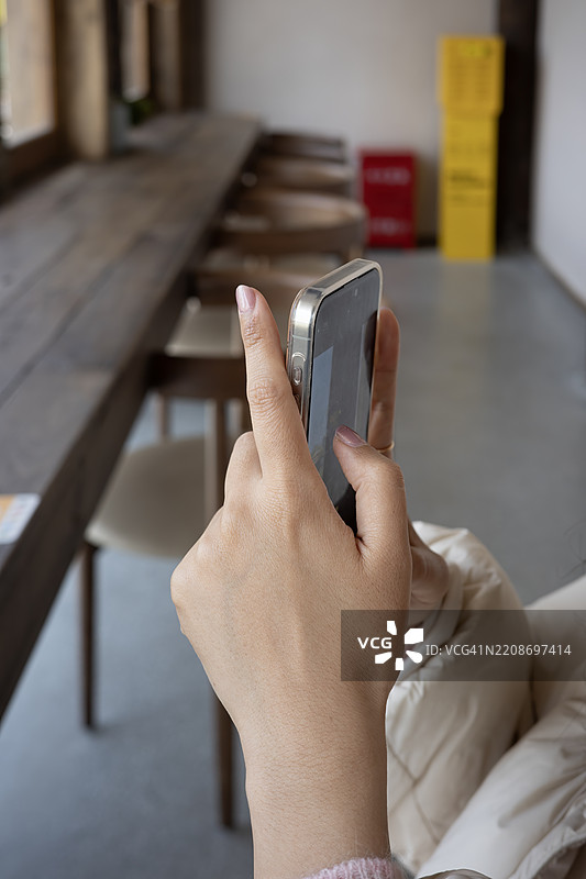 在极简咖啡馆里用智能手机拍照的女性图片素材