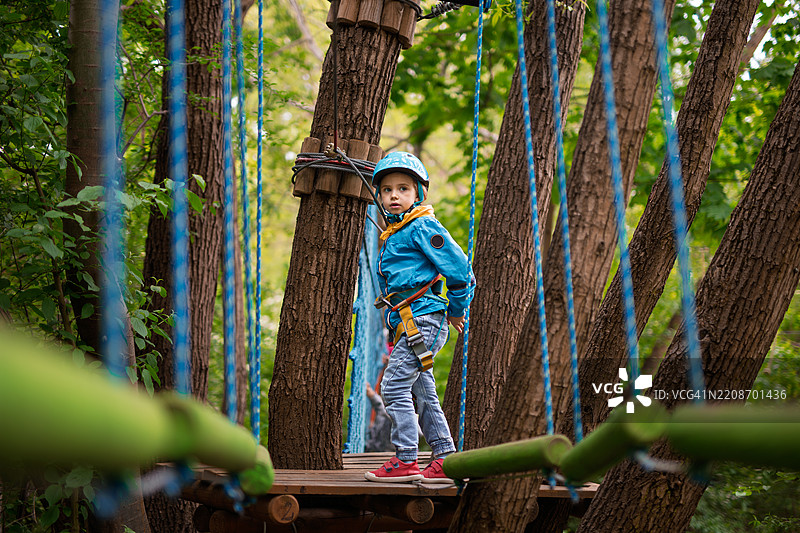 快乐的小女孩在森林中的绳索游乐场准备克服障碍图片素材