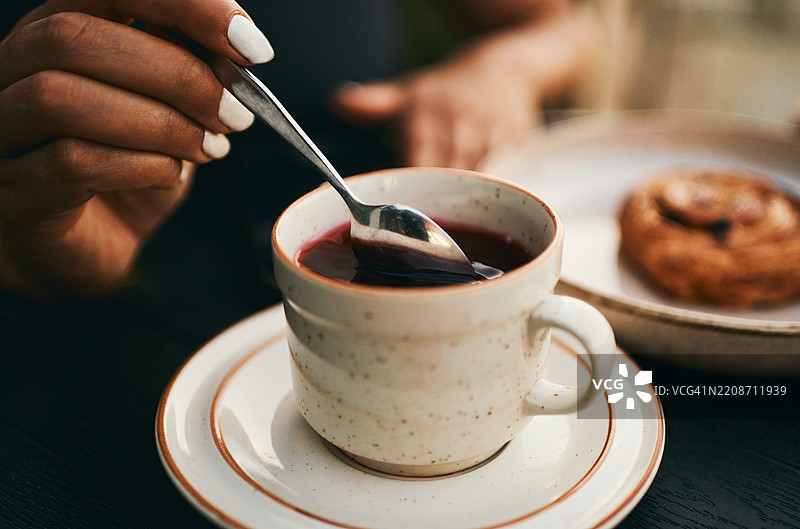 女人正在搅拌热草药茶，旁边有糕点图片素材