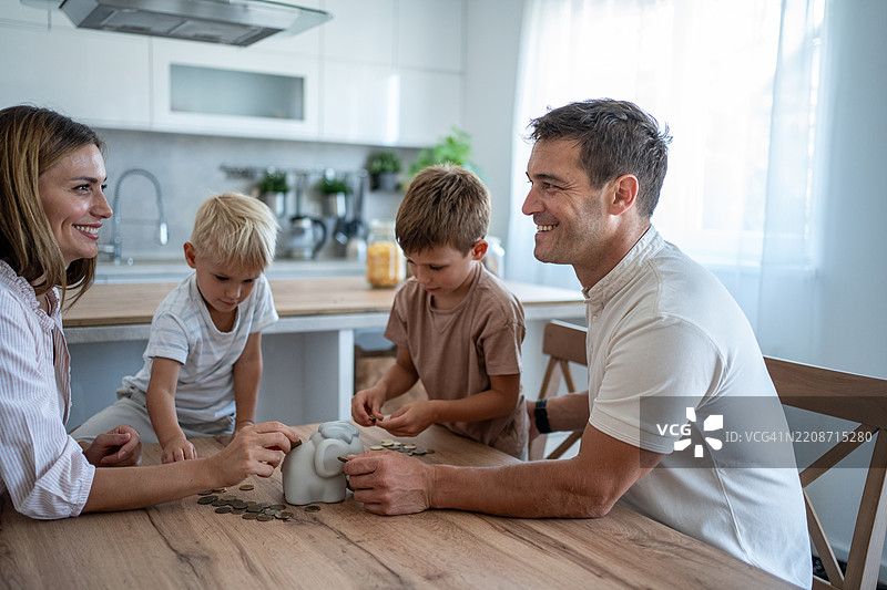 家庭在家一起存钱，把硬币放进储蓄罐里图片素材