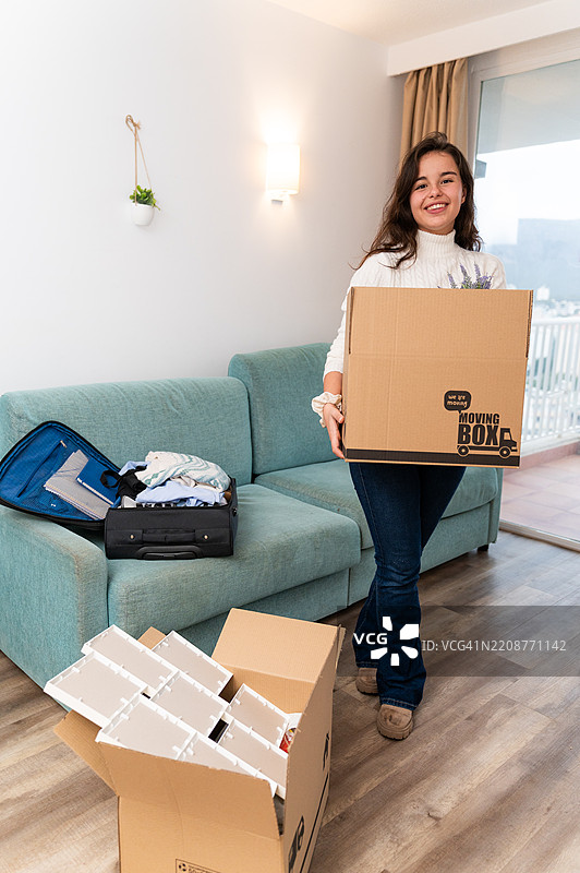 年轻女性搬进新公寓，手里提着箱子图片素材