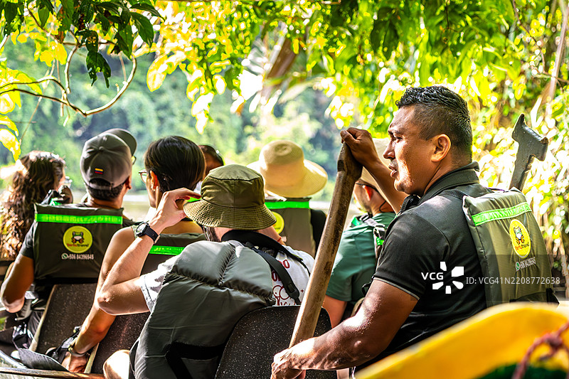 游客在哥斯达黎加的郁郁葱葱的雨林河流中划着导游带领的独木舟图片素材