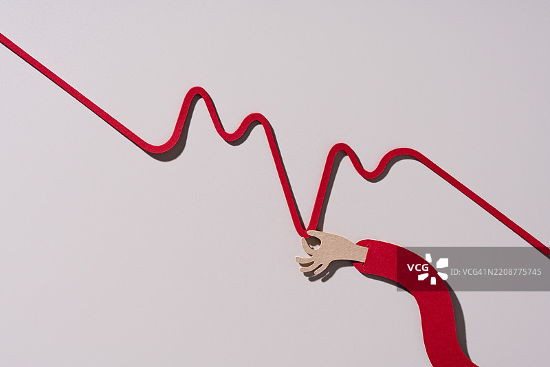 一只手将下跌的折线图拉得更低，纸艺制作图片素材