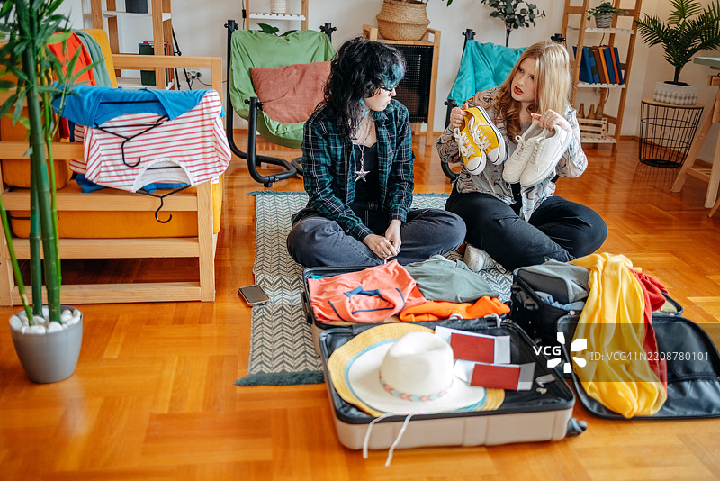 少女们在家中一起打包行李，准备度假，并选择要带的运动鞋。图片素材