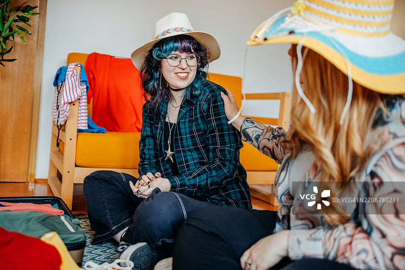 少女们在家中一起打包行李箱，准备度假，并试戴帽子。图片素材