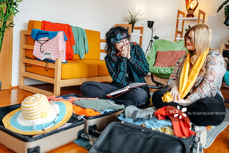 少女们在家中一起打包行李，准备度假，并检查打包清单以确保不忘带东西。图片素材