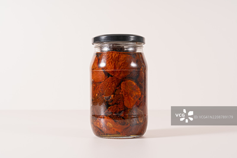米色背景上的玻璃罐装干番茄图片素材