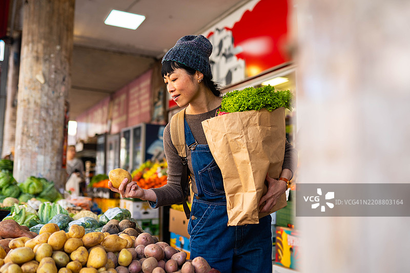 一位女性在市场上挑选蔬菜。图片素材