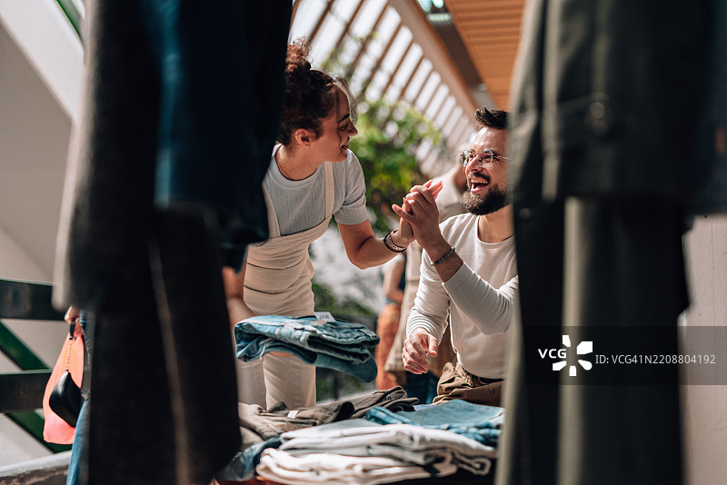 年轻情侣在时尚市场上握手购买可持续服装图片素材