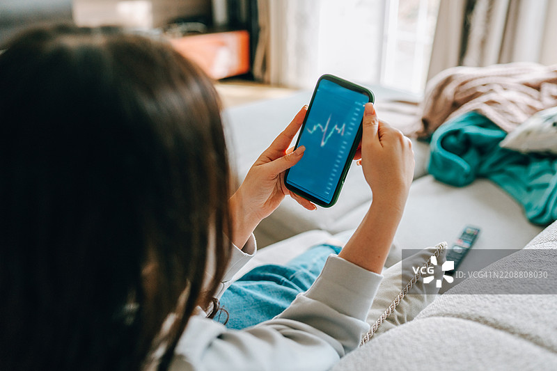 女性在家中用智能手机查看股市行情图片素材