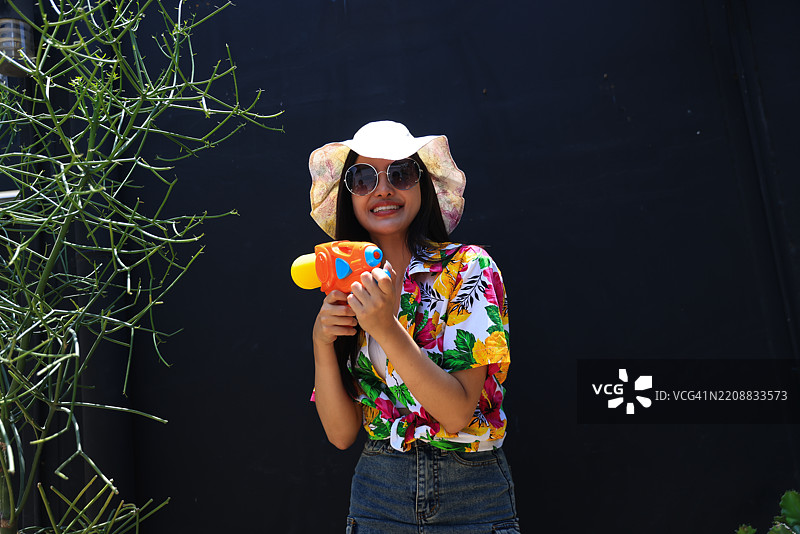 年轻的亚洲女性手持彩色水枪参加泰国宋干节。泰国文化。女性在宋干节中嬉水。图片素材