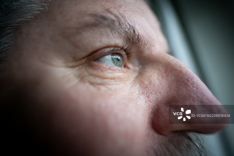 斯堪的纳维亚男子透过窗户凝视的特写镜头图片素材