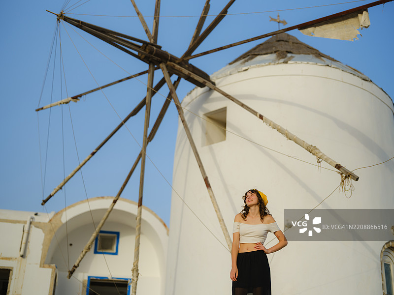 优雅的女性在希腊圣托里尼岛的风车附近漫步图片素材