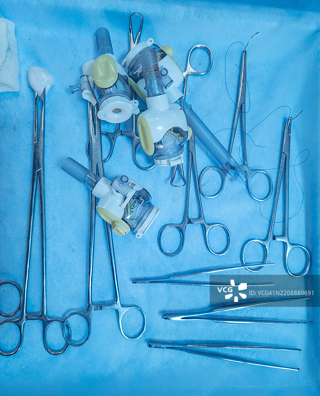 在无菌环境中，手术器械整齐地摆放在蓝色托盘上，准备进行医疗操作。图片素材