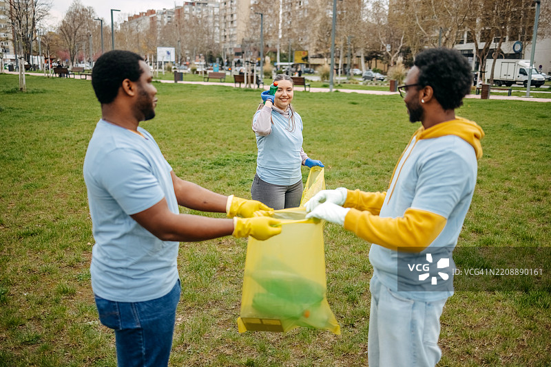一群年轻人在公园里一起快乐地进行社区服务，收集垃圾。图片素材