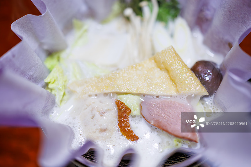 奢华的豆浆火锅，里面装满了鸭肉、本地蔬菜和鱼。锅是用日本纸制成的。图片素材