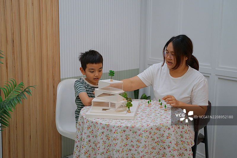 母亲在客厅教孩子关于建筑的知识。图片素材