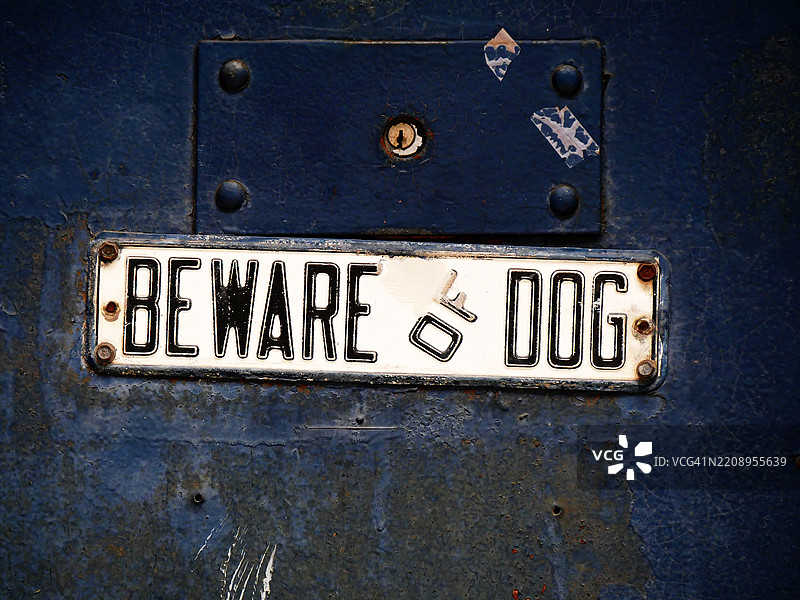 猎人点（长岛市），纽约市，美国一扇肮脏且有古旧感的蓝色门上贴着“当心狗”的标志。自然色彩。阳光照射。图片素材