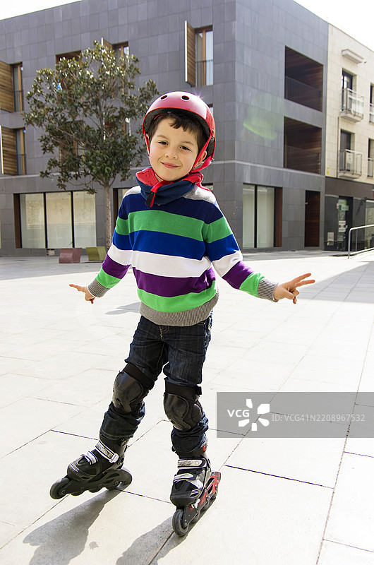 一个戴着红色头盔的孩子在户外穿着轮滑的背影图片素材