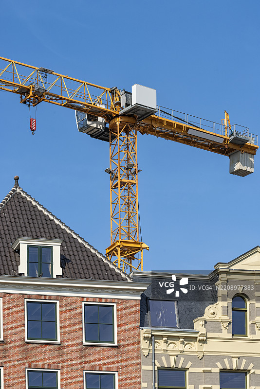 工业起重机高高耸立在建筑物的屋顶上，映衬着晴朗的蓝天图片素材