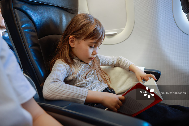 女孩在飞机上阅读一本书图片素材