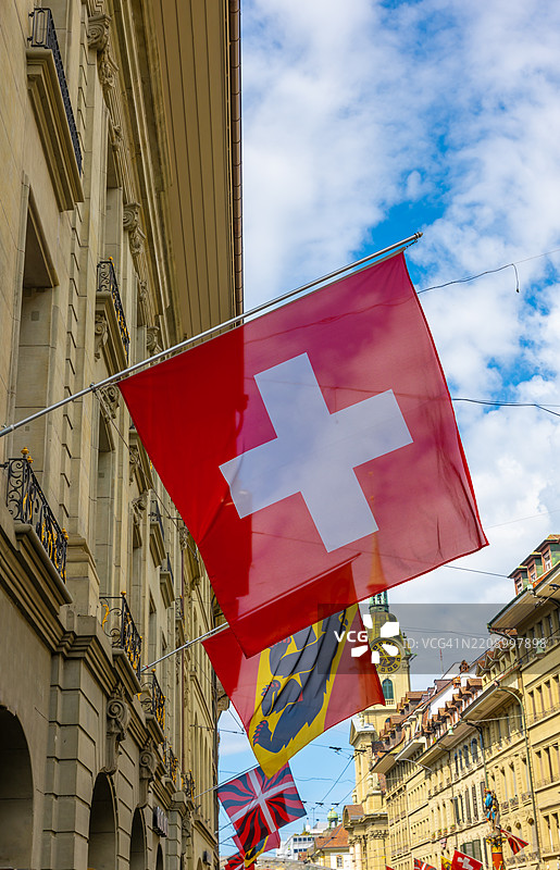 美丽的老城区街道，古老的建筑和阳光明媚的夏日里飘扬的旗帜，位于伯尔尼市。图片素材