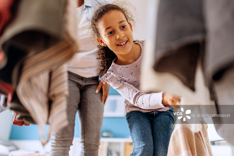 母亲和女儿在家中从衣柜中挑选衣服图片素材