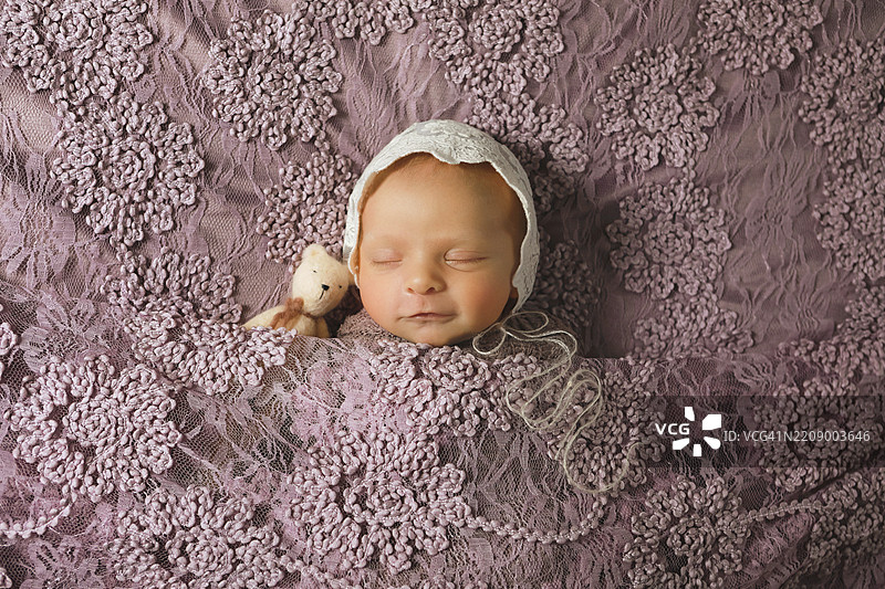 新生女婴与泰迪熊安静入睡图片素材