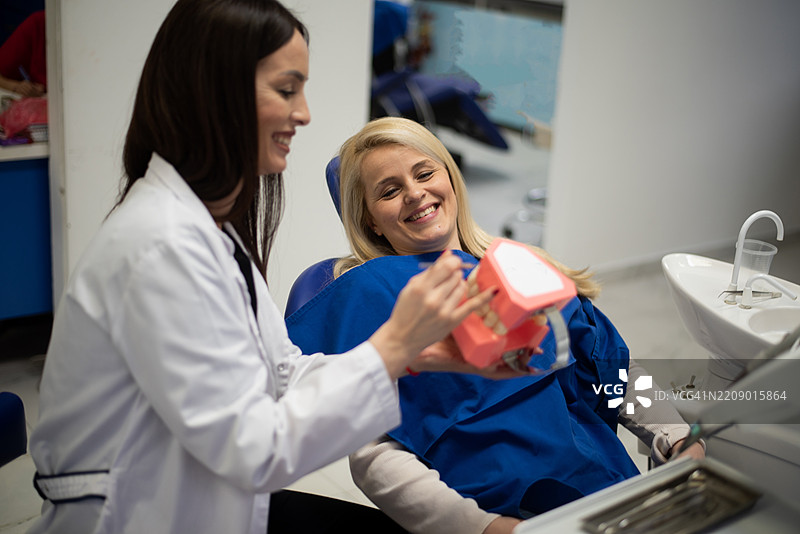 漂亮的女牙医在牙科诊所为颌模型刷牙图片素材