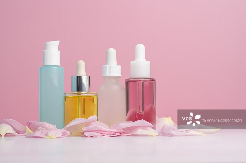 各种护肤瓶子在粉色背景上图片素材