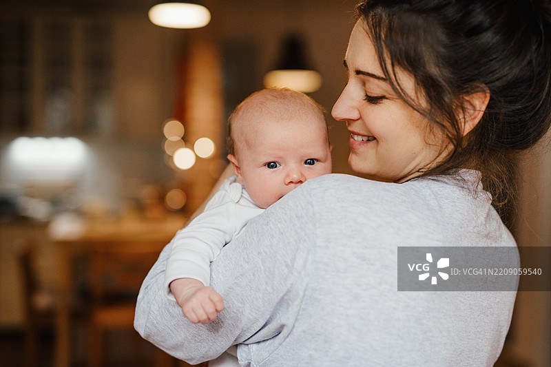母亲将女儿抱在肩上。图片素材