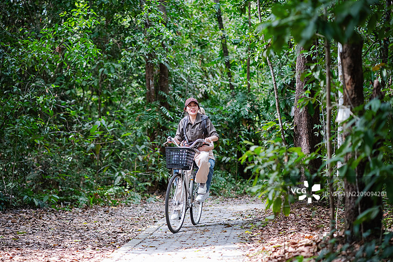 两个兄妹骑着自行车在森林中观察自然。图片素材