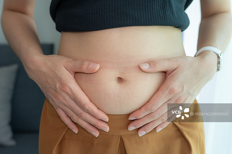 怀孕一个月的女性抱着自己的肚子特写镜头。图片素材