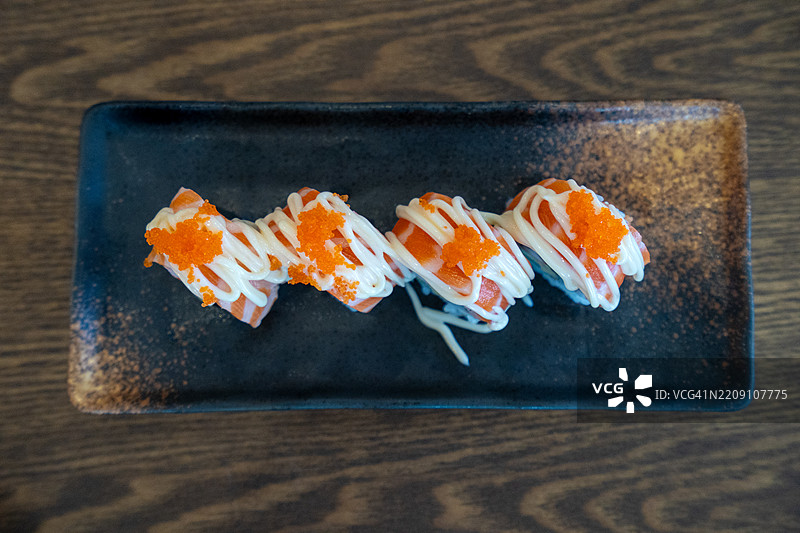 各种新鲜三文鱼和金枪鱼寿司卷，盛放在传统日本盘子上图片素材