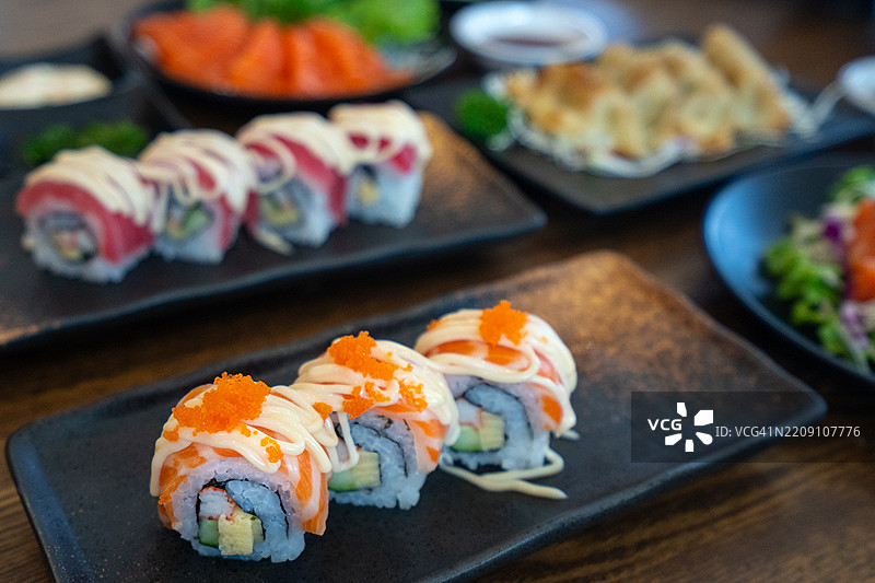 各种新鲜三文鱼和金枪鱼寿司卷，盛放在传统日本盘子上图片素材