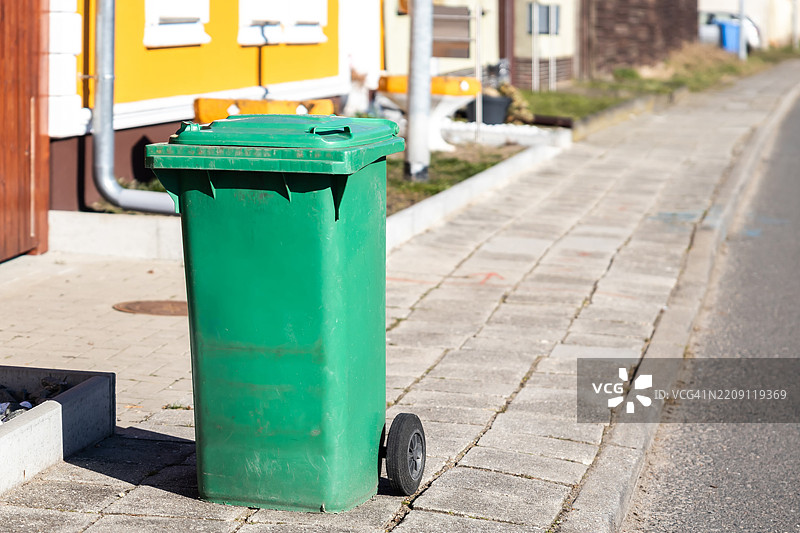 住宅区人行道上的绿色垃圾桶图片素材