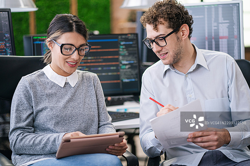 软件程序员分析HTML代码和数据库，集思广益，构思开发新安全系统的脚本创意。工程师们在小组项目中合作使用编程语言。图片素材