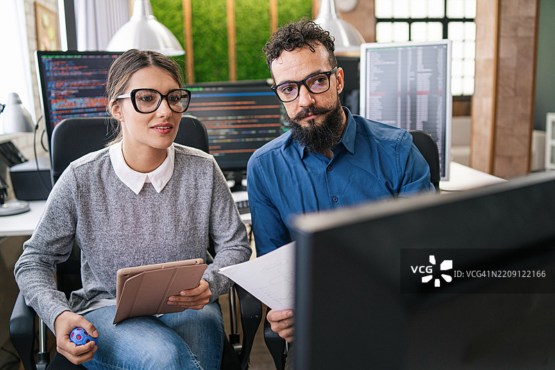 软件程序员分析HTML代码和数据库，集思广益，构思开发新安全系统的脚本创意。工程师们在小组项目中合作使用编程语言。图片素材