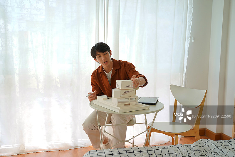 这个男人正在制作建筑模型。图片素材