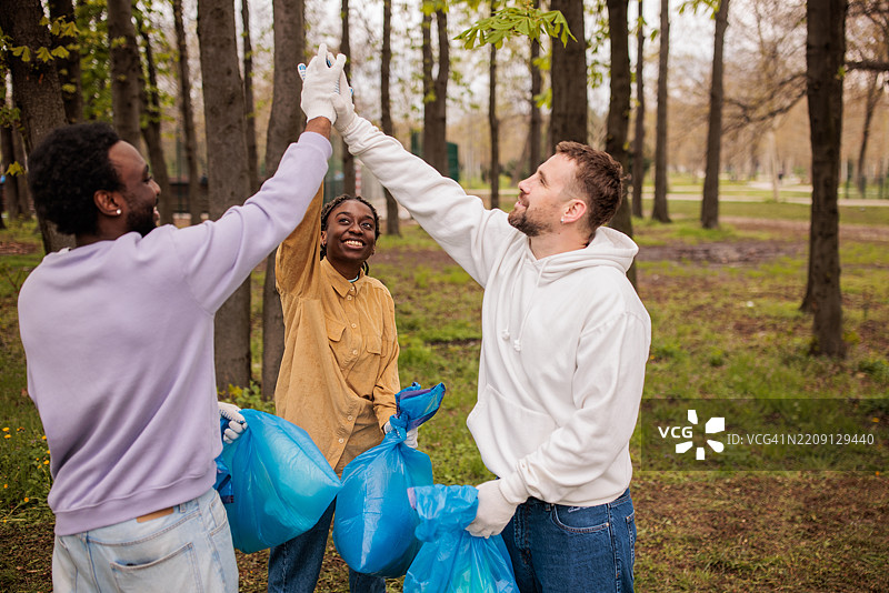 环保活动家在他们清理的森林中击掌庆祝图片素材