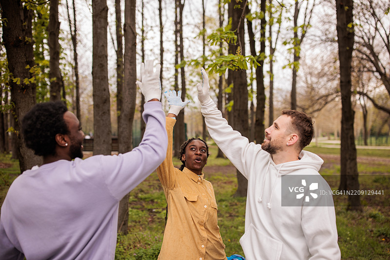 环保活动家在他们清理的森林中击掌庆祝图片素材