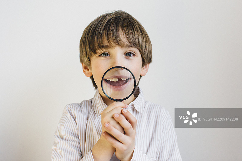 快乐的男孩用放大镜观察自己的牙齿图片素材