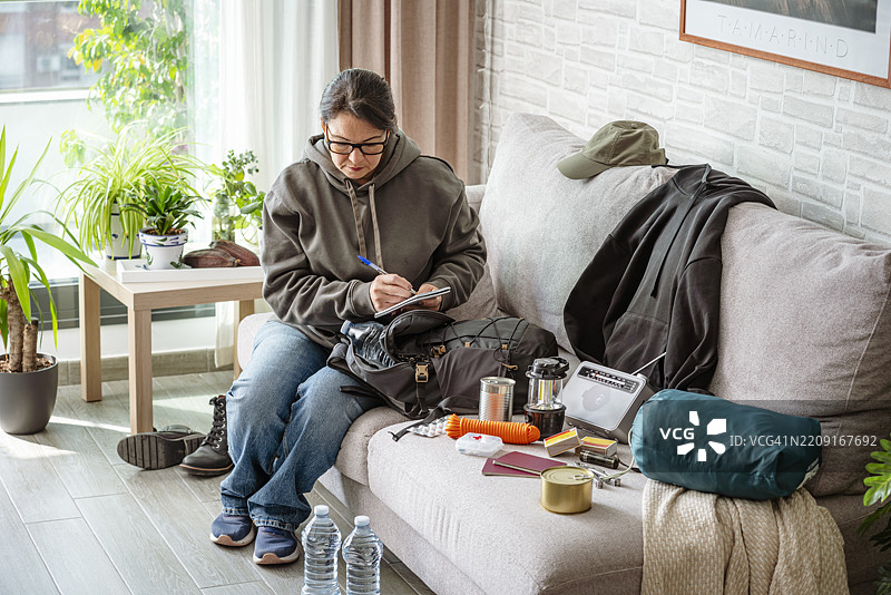女性在检查应急生存包清单。为家庭灾难和危机做好准备图片素材